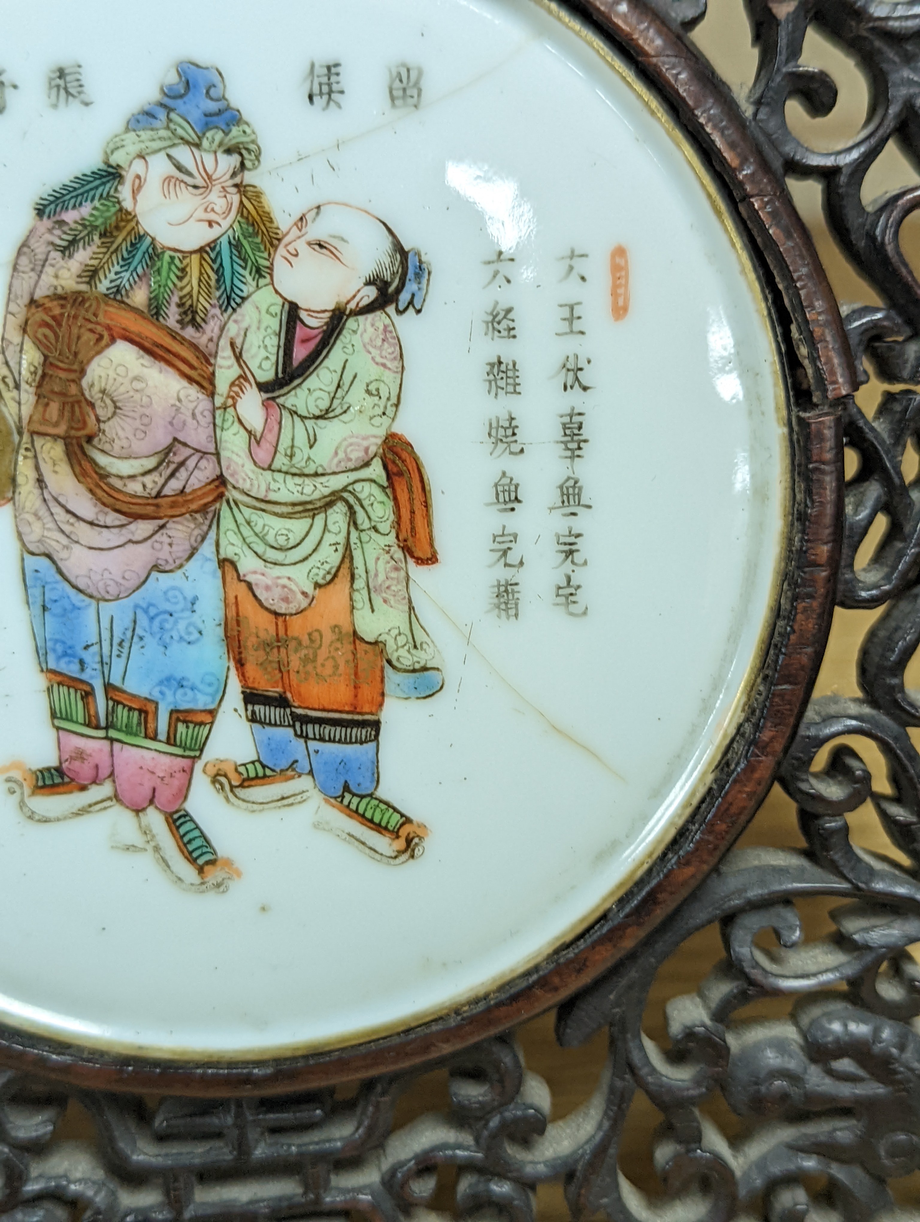 A 19th century Chinese famille rose circular plaque or cover, inset into a wood surround, cracks 15cm sq